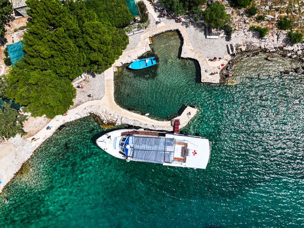 Aerial view of Flipper One boat docked in Pakoštane, Croatia, surrounded by crystal-clear sea and lush Mediterranean coastline — starting point for Kornati and Telašćica boat tours.