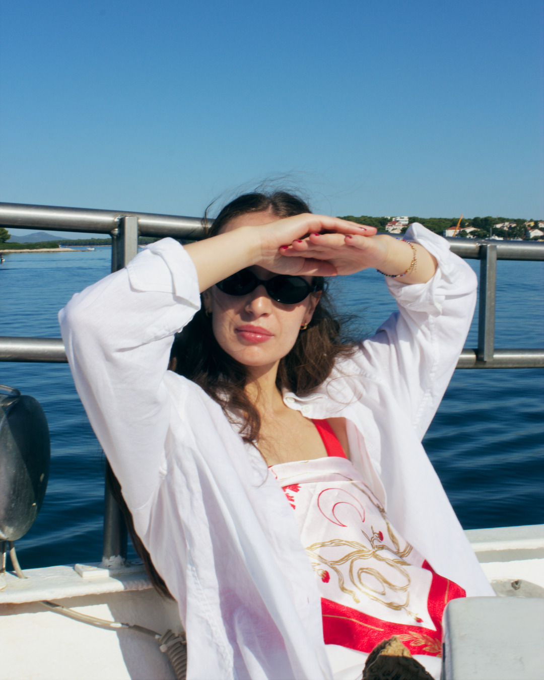 Woman shielding her eyes from the sun while standing on a boat during a Flipper One excursion in Croatia.