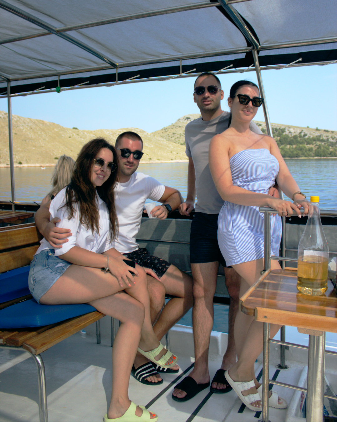 Group of friends enjoying drinks and sunshine on the deck of Flipper One during an island-hopping tour.