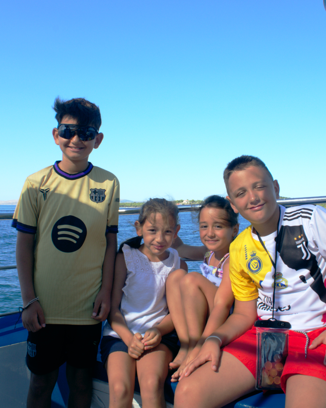 Group of smiling children and adults posing on a boat during a family-friendly Kornati tour.